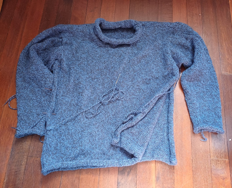 A dark blue roll-neck jumper with the side seams unfinished.