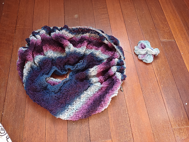 A partially knitted circular shawl, still on the needles and rather scrunched up.