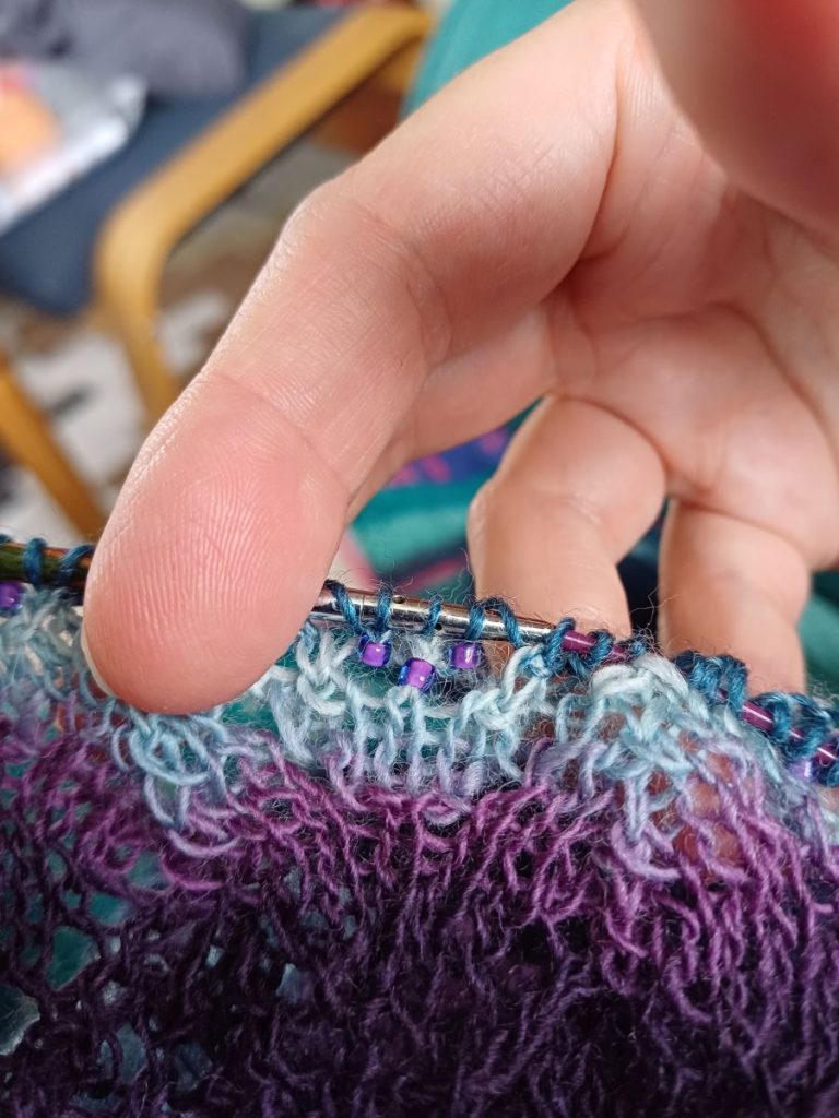 Picture shows a piece of knitting on the needles, including some tiny beads. 